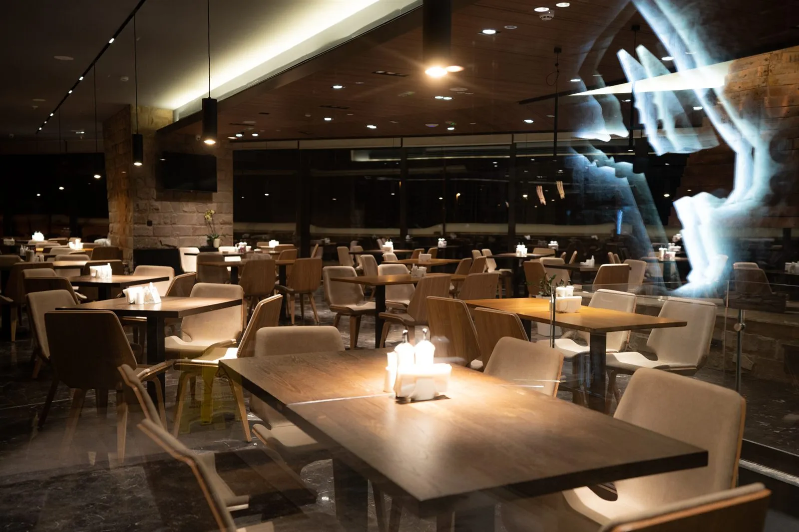 A restaurant in the evening — wooden tables, upholstered chairs and candles on the tables