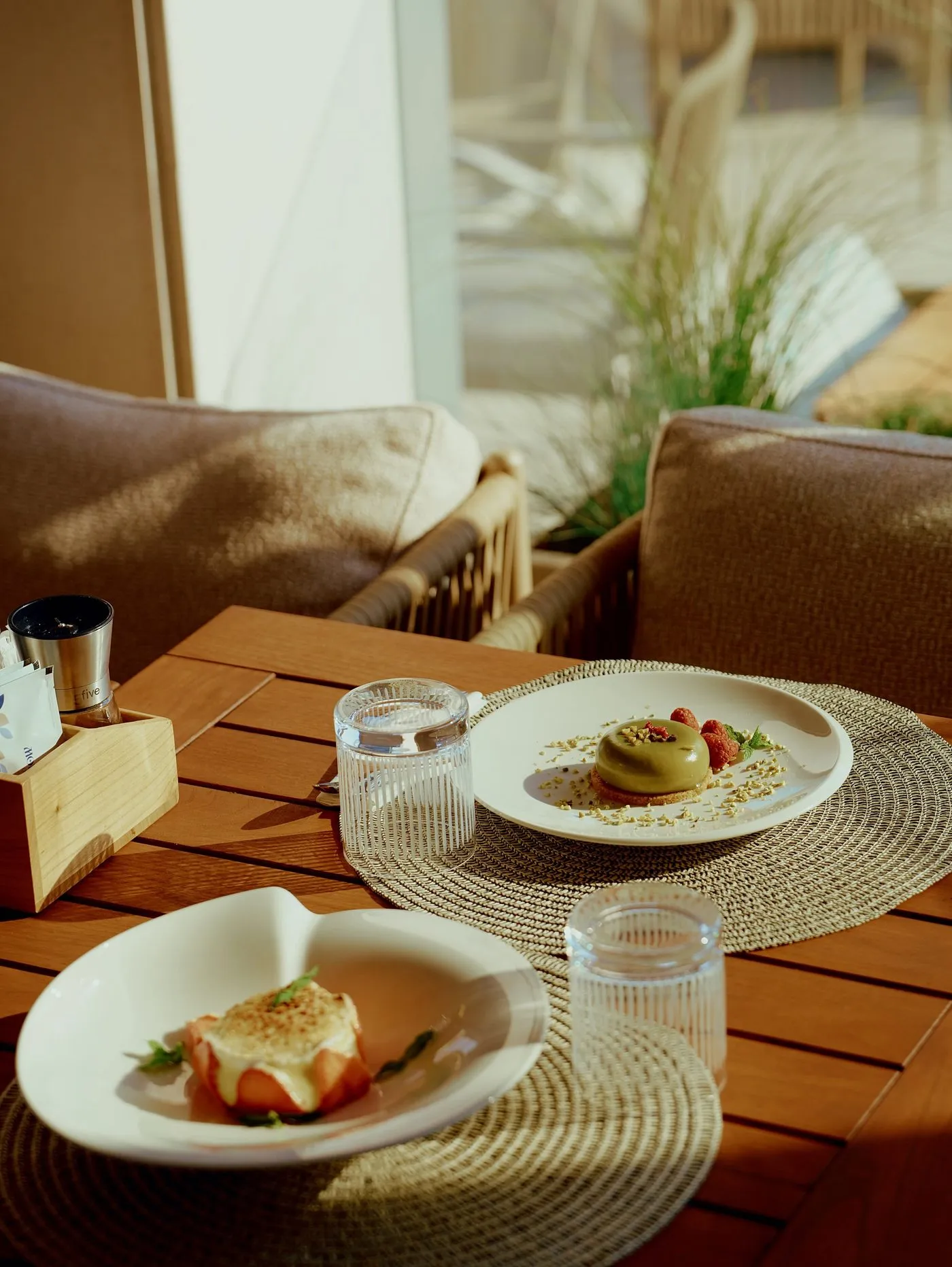 The Monument a mare terrace with woven armchairs and a wooden table set with desserts